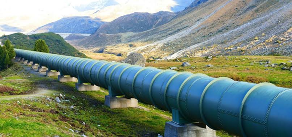 Una empresa colombiana es la única que con sus pipetas le pelean a 4 gigantes chilenas en el negocio de gas propano Blue industrial pipeline elevated on concrete supports traverses a green valley with mountains in the distance, transporting fluids across the terrain. - Una empresa colombiana es la única que con sus pipetas le pelean a 4 gigantes chilenas en el negocio de gas propano