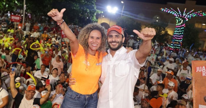 El espaldarazo de Fico Gutiérrez que metió a la Profe cordobesa Natalia López en el gabinete del Tigre Dos voluntarios de la campaña posan en el escenario con los brazos alrededor, con multitudes animadas detrás en una plaza exterior festiva.
