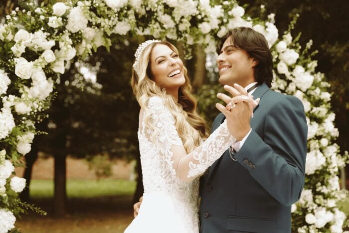 Bride and groom laughing and dancing under a white rose arch at an outdoor wedding event. - La infidelidad de Nicolás Petro prendió el incendio que tiene enfrentadas y cerca de la cárcel a su esposa y a su ex
