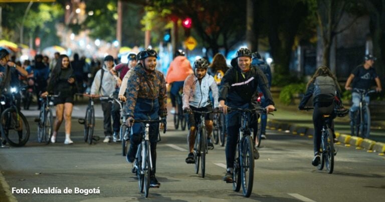 Las2orillas.co: Historias, voces y noticias de Colombia Group of cyclists riding on a city street at night during a bike event, with spectators in the background, many wearing helmets and jackets. - Las2orillas.co: Historias, voces y noticias de Colombia
