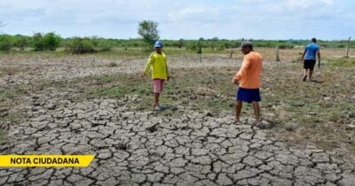 Three people walk across a cracked, dry field under a blue sky, highlighting drought conditions on the land (NOTA CIUDADANA banner bottom left). - Las2orillas.co: Historias, voces y noticias de Colombia