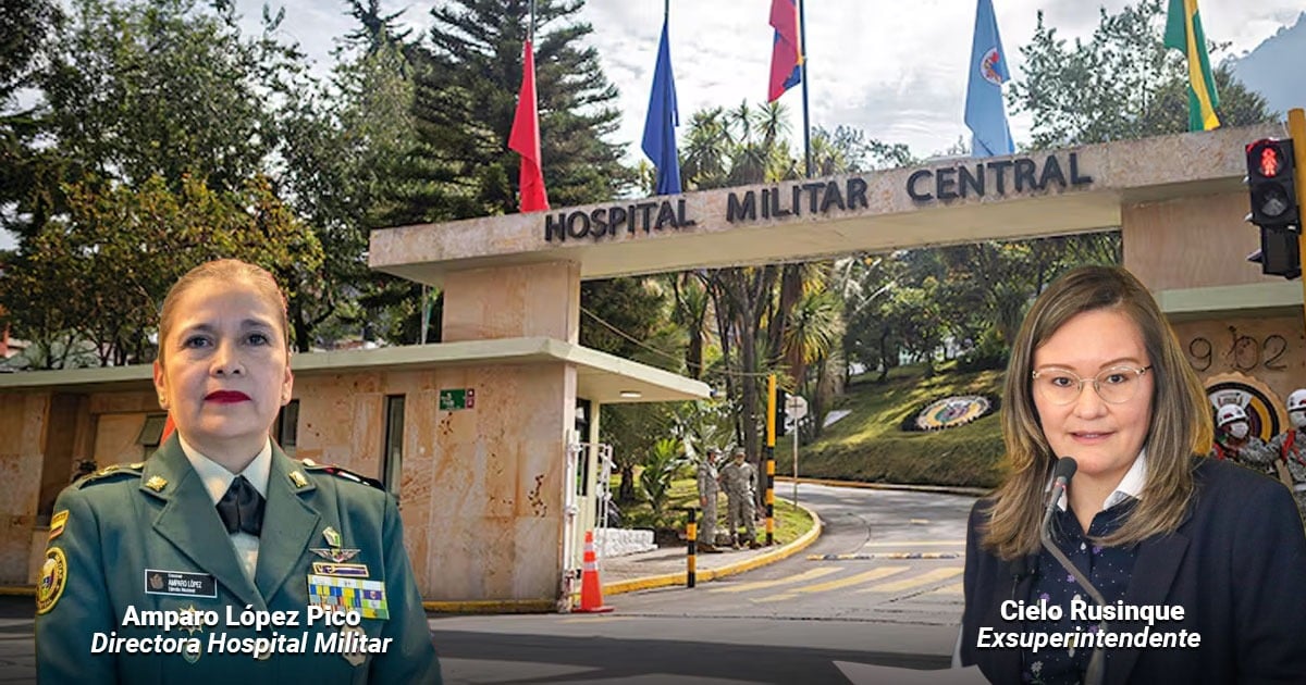 Two women stand at the Hospital Militar Central entrance: a uniformed director on the left and a suited speaker with a microphone on the right. - La coronel médica que se estrena como directora del Hospital Militar hereda una dura multa por un contrato que no firmó