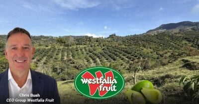 Las2orillas.co: Historias, voces y noticias de Colombia Portrait of Chris Bush, CEO of Westfalia Fruit, in a suit against a farm landscape with the company logo and fruit imagery in the foreground. - Las2orillas.co: Historias, voces y noticias de Colombia