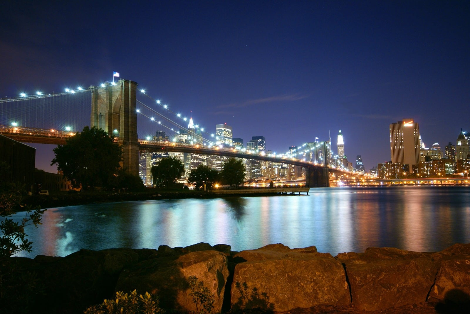 El ingeniero paisa que tendió el puente de Occidente, después de haber aprendido en el de Brooklyn, en NY Night view of the Brooklyn Bridge and the Manhattan skyline across a reflective river at night. - El ingeniero paisa que tendió el puente de Occidente, después de haber aprendido en el de Brooklyn, en NY