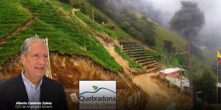 Las2orillas.co: Historias, voces y noticias de Colombia Man in a suit stands in front of a terraced, green hillside mining site with the Quebradona Minera de Cobre logo visible in the foreground. - Las2orillas.co: Historias, voces y noticias de Colombia