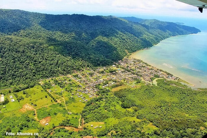 Luego de 4 años de retrasos, adiciones y mil millones invertidos Bahía Solano, en Chocó, estrena aeropuerto Aerial view of a coastal town nestled between lush green hills and a calm bay. Readable and concise for navigation or article context.