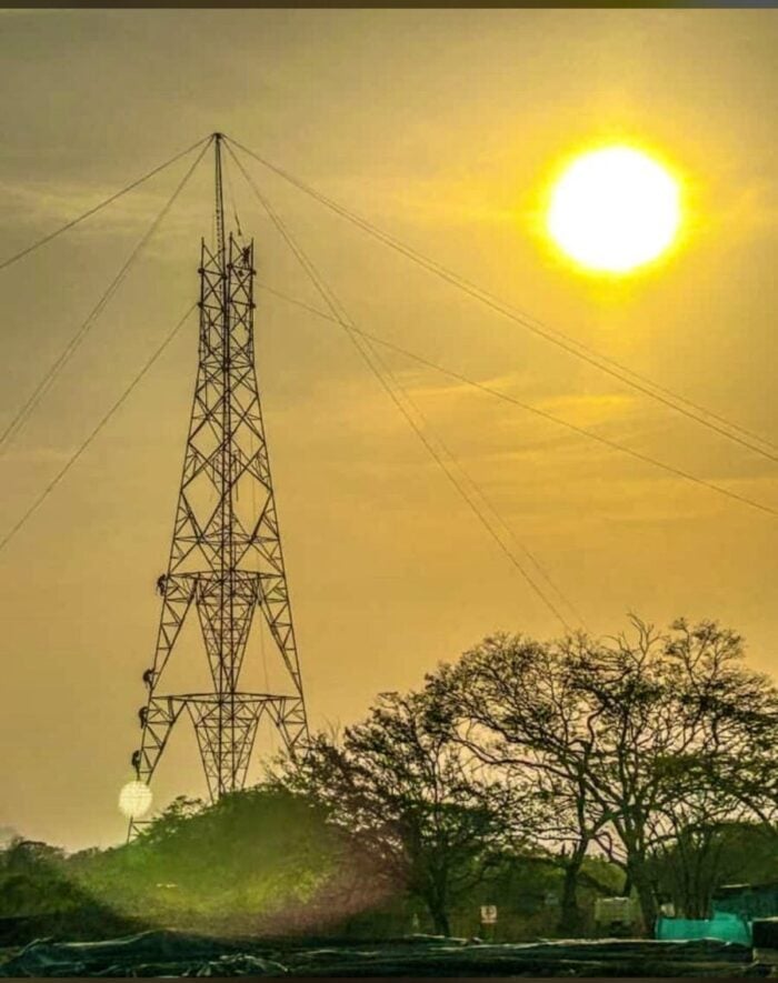 Después de 10 años se logrará al fin enviar energía a Bogota a través de un conector que une a Boyacá y Santander Tall metal lattice transmission tower with power lines against an orange sunset and trees in the foreground. - Después de 10 años se logrará al fin enviar energía a Bogota a través de un conector que une a Boyacá y Santander