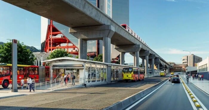 Bus stop at a modern transit station with a raised elevated rail line and buses on the curbside. - Que hicieron y que dejaron de hacer los 3 presidentes y 4 últimos Alcaldes de Bogotá por el Metro