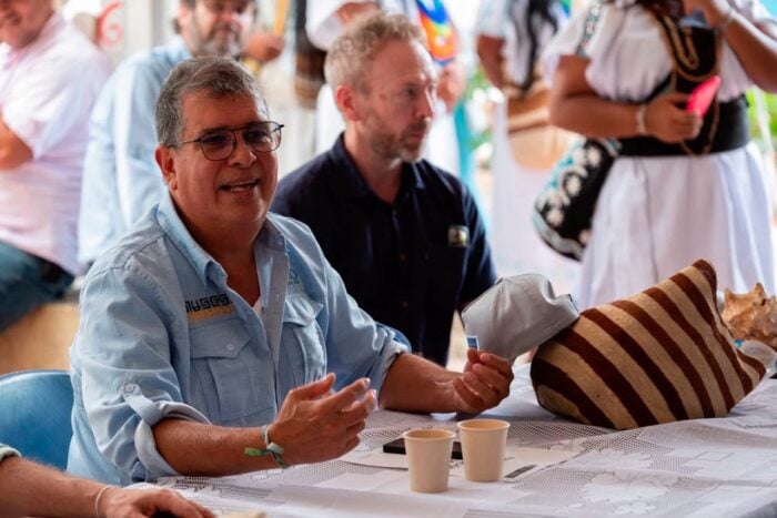 Cómo pequeños operadores desplazaron a gigantes del turismo como Aviatur y Decameron de los Parques Nacionales Man in a light blue shirt speaks at a table during a crowded event, gesturing with his hands as others listen in the background. - Cómo pequeños operadores desplazaron a gigantes del turismo como Aviatur y Decameron de los Parques Nacionales
