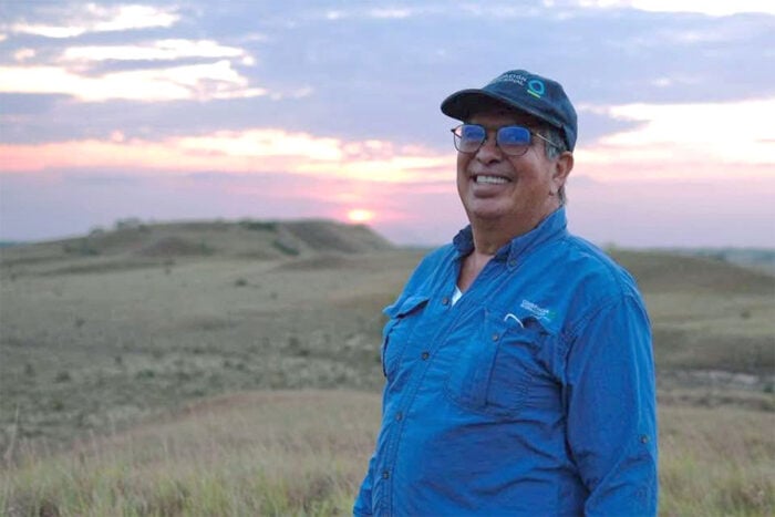 La santandereana detrás de la tutela que tumbó el decreto con el que Petro quiso detener la minería en Santurbán Smiling man in a blue shirt and cap stands in a grassy plain at sunset. - La santandereana detrás de la tutela que tumbó el decreto con el que Petro quiso detener la minería en Santurbán