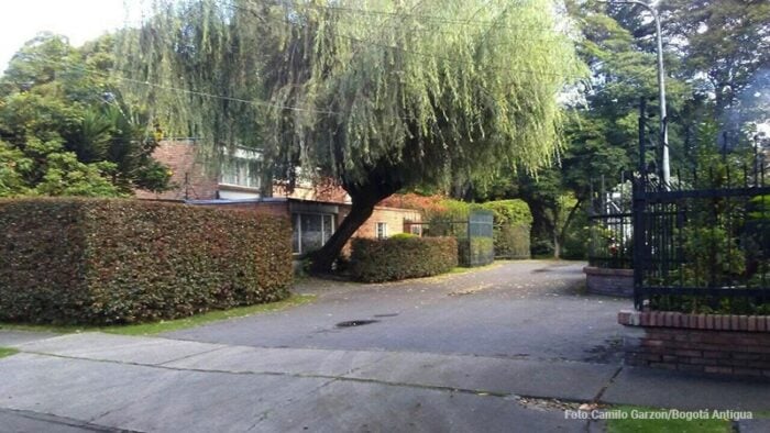 La antigua Hacienda Niza de la familia hurtado en Bogotá termino dando el nombre al barrio Niza de Suba. Residential street scene with a large weeping tree arching over a driveway, trimmed hedges, and a wrought-iron gate - La antigua Hacienda Niza de la familia hurtado en Bogotá termino dando el nombre al barrio Niza de Suba.