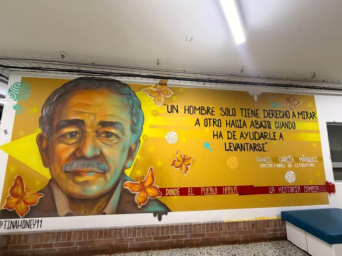 Quién es la nueva directora de Inravisión que llegó a borrar toda huella de Petro y Hollman Morris Portrait of Gabriel García Márquez on a vibrant yellow mural with orange butterflies and a Spanish quote about helping others up from the ground. - Quién es la nueva directora de Inravisión que llegó a borrar toda huella de Petro y Hollman Morris