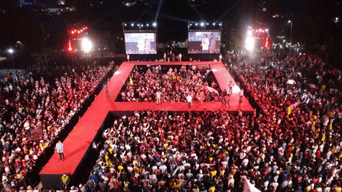 Se le acabó la fiesta a Euclides Torres, el financiador de Petro y Benedetti, con sus negocios alrededor del tránsito Aerial view of a large outdoor fashion show with a bright red U-shaped runway, audience on both sides, and stage with screens in the background. - Se le acabó la fiesta a Euclides Torres, el financiador de Petro y Benedetti, con sus negocios alrededor del tránsito