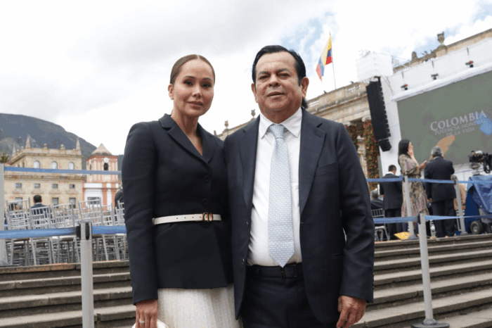 Se le acabó la fiesta a Euclides Torres, el financiador de Petro y Benedetti, con sus negocios alrededor del tránsito Two formally dressed people pose for a photo at an outdoor event on steps, with a stage and Colombian flag in the background. - Se le acabó la fiesta a Euclides Torres, el financiador de Petro y Benedetti, con sus negocios alrededor del tránsito