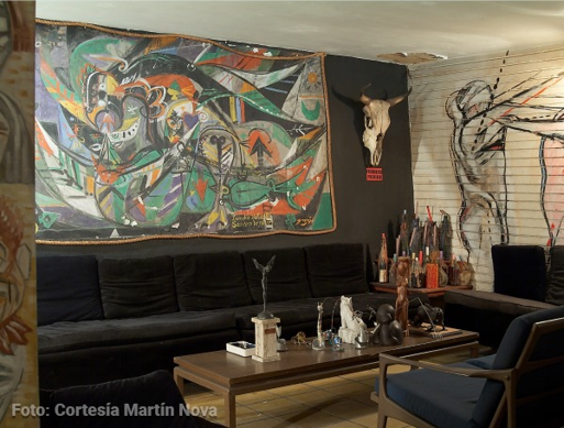 Fue un mexicano quien rescató de un sótano en Medellín los primeros murales que pintaron Botero y Obregón Colorful abstract mural on the wall with a mounted bull skull, plus a cozy lounge area and a wooden coffee table with sculptures and decor. - Fue un mexicano quien rescató de un sótano en Medellín los primeros murales que pintaron Botero y Obregón