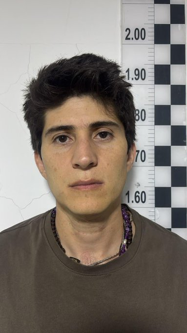 El infierno del exsenador Wadith Manzur en La Picota, su nuevo lugar de reclusión Front-facing person with short dark hair and a brown shirt stands against a height-measuring wall, around 1.75 m tall; mugshot-style photo with neutral expression and a necklace. - El infierno del exsenador Wadith Manzur en La Picota, su nuevo lugar de reclusión