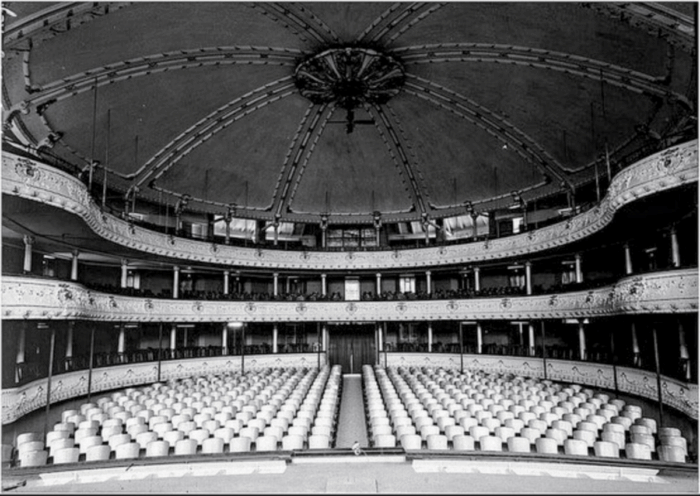 El paisa que terminó detrás de Cien años de soledad y trabajando con J Balvin, Feid y Juanes Black-and-white interior of a historic theater with three ornate balconies and rows of empty seats facing the stage. - El paisa que terminó detrás de Cien años de soledad y trabajando con J Balvin, Feid y Juanes