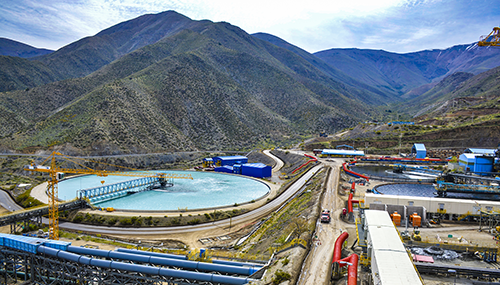 Los negocios que llevaron a la cima a los cinco más ricos de América Latina entre los que hay un colombiano Industrial mining site in a mountainous valley featuring a circular tailings pond, blue processing buildings, and network of roads and conveyors. - Los negocios que llevaron a la cima a los cinco más ricos de América Latina entre los que hay un colombiano