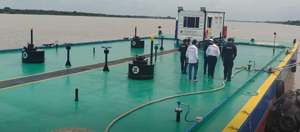 Una empresa Barranquillera logró producir barcos que tanquean en alta mar People in white shirts stand on a green deck barge with a small control cabin; a hose is laid across the deck beside equipment. - Una empresa Barranquillera logró producir barcos que tanquean en alta mar
