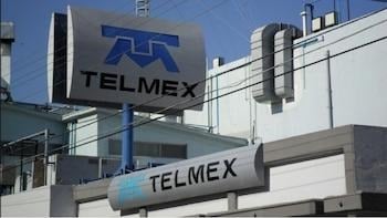 Los negocios que llevaron a la cima a los cinco más ricos de América Latina entre los que hay un colombiano Telmex logo signs mounted on a blue pole in front of a building outside view. - Los negocios que llevaron a la cima a los cinco más ricos de América Latina entre los que hay un colombiano