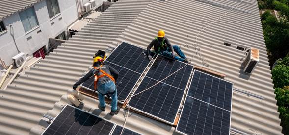 Los 2 italianos que junto al español amigo de Petro y Verónica Alcocer aparecen en el escándalo de Ecopetrol Three construction workers in hard hats and safety gear install a solar panel array on a corrugated metal roof on a sunny day. - Los 2 italianos que junto al español amigo de Petro y Verónica Alcocer aparecen en el escándalo de Ecopetrol