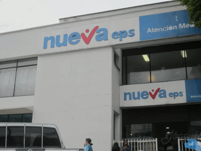 El panorama de quiebra irreversible con el que se encuentra el recién llegado interventor de la Nueva EPS Facade of a medical clinic with blue 'nueva eps' signs and a blue 'Atención Médica' panel above the entrance. - El panorama de quiebra irreversible con el que se encuentra el recién llegado interventor de la Nueva EPS