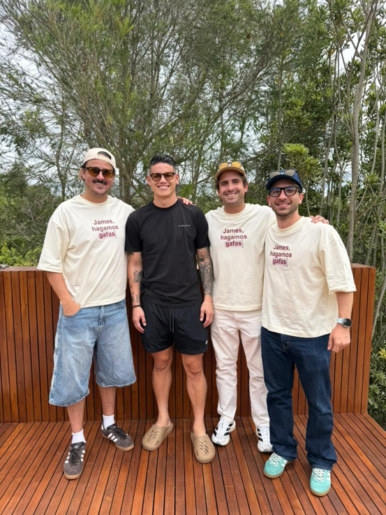 Gilinski retomó la ruta y ahora otras 6 empresas colombianas van por el nuevo mercado venezolano Four men posing on a wooden outdoor deck, smiling; three wear cream shirts with red text and sunglasses, one in a black shirt. - Gilinski retomó la ruta y ahora otras 6 empresas colombianas van por el nuevo mercado venezolano