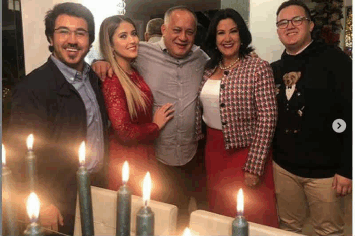 El derrumbe de Diosdado Cabello, quien ahora podría terminar en una cárcel en Santiago de Chile vinculado a un asesinato Five adults posing for a photo at a festive dinner, with tall candles burning in the foreground. - El derrumbe de Diosdado Cabello, quien ahora podría terminar en una cárcel en Santiago de Chile vinculado a un asesinato
