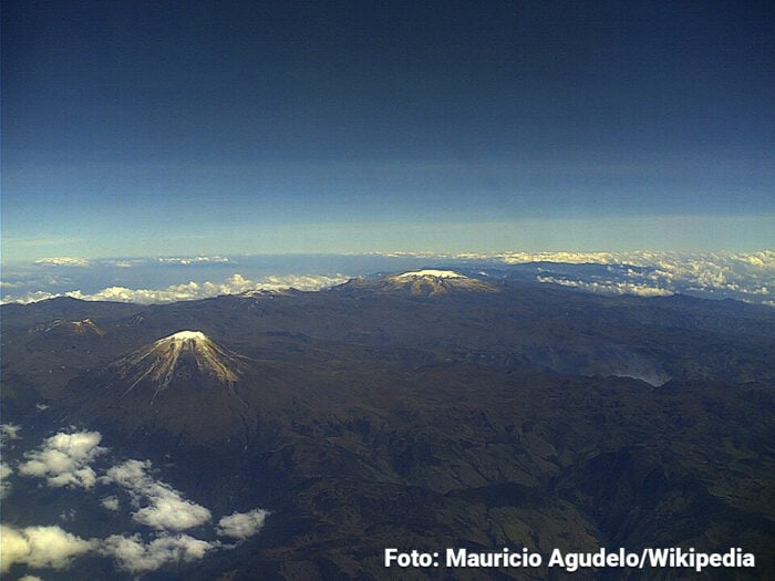 Cómo pequeños operadores desplazaron a gigantes del turismo como Aviatur y Decameron de los Parques Nacionales Aerial view of snow-topped volcanic cones in a rugged brown landscape, with a clear blue sky and distant clouds. - Cómo pequeños operadores desplazaron a gigantes del turismo como Aviatur y Decameron de los Parques Nacionales