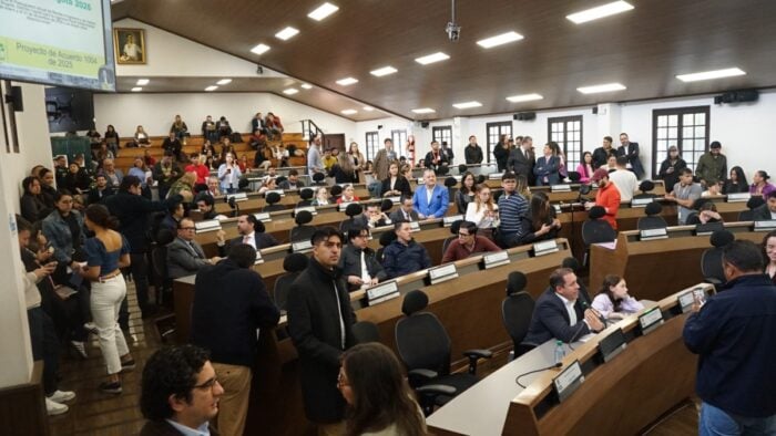 Los cuatro concejales de Bogotá que le salvaron a Galán el impuesto al alumbrado que 6 alcaldes no lograron Large conference chamber filled with people seated at curved desks and others standing, indicating a formal meeting or assembly. - Los cuatro concejales de Bogotá que le salvaron a Galán el impuesto al alumbrado que 6 alcaldes no lograron