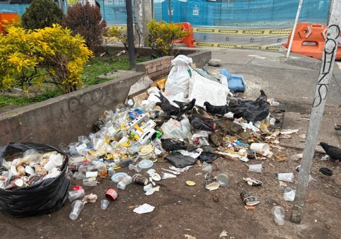 El fracasada estrategia de Galán para limpiar la ciudad de basuras que ha costado .000 millones y no ha servido Overflowing pile of trash and discarded cups on a sidewalk near a construction site barrier area. - El fracasada estrategia de Galán para limpiar la ciudad de basuras que ha costado .000 millones y no ha servido
