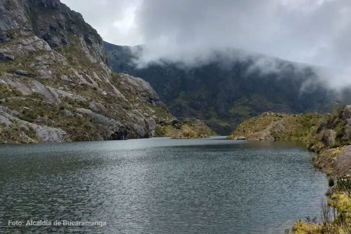 La santandereana detrás de la tutela que tumbó el decreto con el que Petro quiso detener la minería en Santurbán Calm lake bordered by rugged rocky slopes with misty clouds over distant hills in the background. - La santandereana detrás de la tutela que tumbó el decreto con el que Petro quiso detener la minería en Santurbán