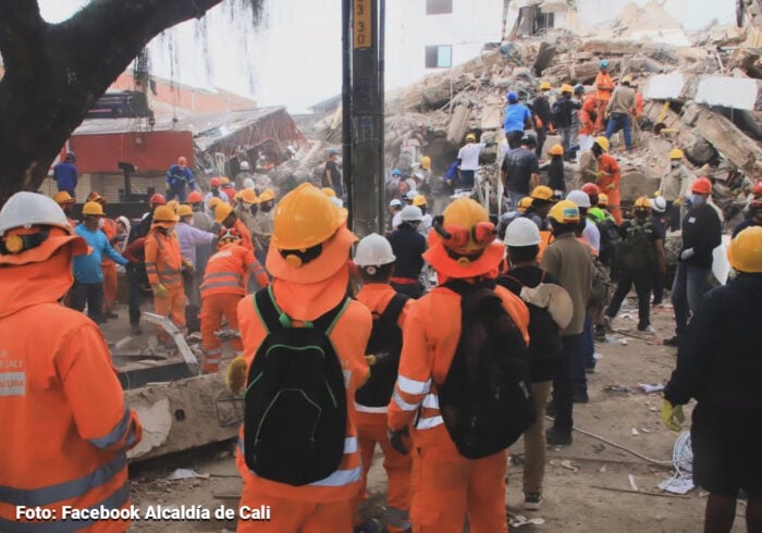 Emergency responders in orange uniforms and hard hats work amid rubble after a building collapse at a disaster site. - El internet gratis de Elon Musk tras el terremoto en Colombia disparó 40% el uso de Starlink en departamentos golpeados