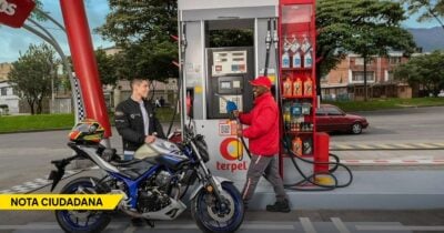 Two men at a Terpel gas pump: a rider on a blue-silver motorcycle chats with a attendant in a red jacket while fueling the bike . - Las2orillas.co: Historias, voces y noticias de Colombia