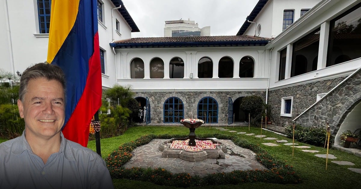 Smiling man in a blue shirt stands in a courtyard with a central fountain, a tall multicolor flag on the left, and a white building with blue arches in the background. - El exsenador que lideró la campaña del No contra el acuerdo de Santos y las Farc que De la Espriella envía a Ecuador