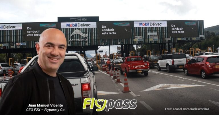 Las2orillas.co: Historias, voces y noticias de Colombia Smiling man in a black jacket stands by a white pickup in a toll plaza, Flypass branding visible on the foreground graphic and traffic in the background. - Las2orillas.co: Historias, voces y noticias de Colombia