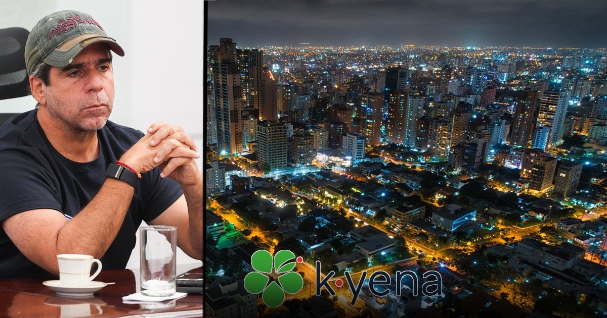 Man in a cap sits at a table, with a nighttime cityscape and a kyena logo on a large screen beside him. - La alianza público-privada que armó el alcalde Char apara el programa Internet con propósito en Barranquilla