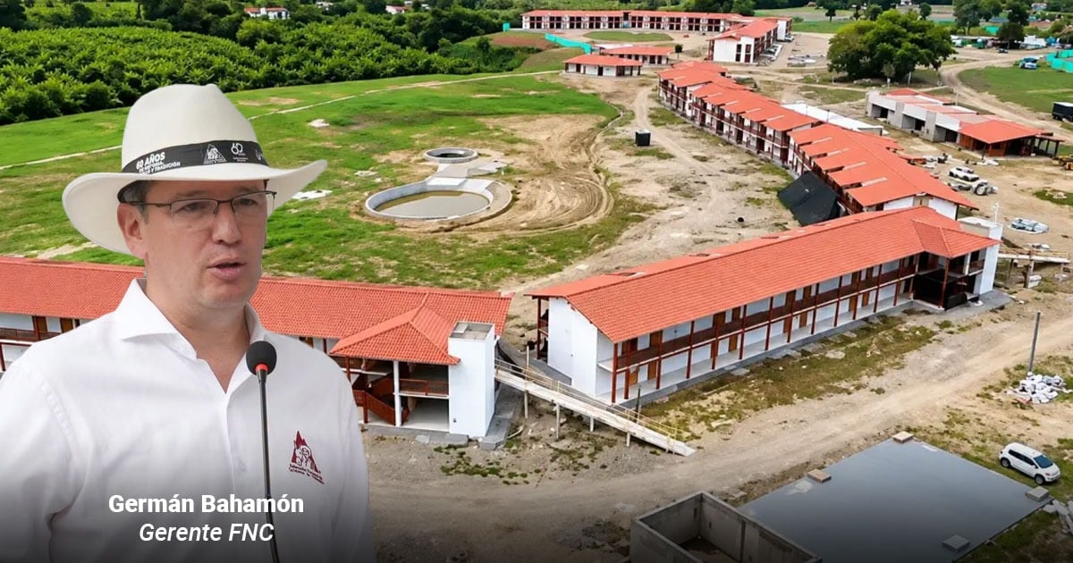 Man in a white shirt and white hat speaks into a microphone at a construction site with red-roofed buildings in the background. - La Federación de Cafeteros se mete al negocio hotelero con un megaproyecto frente al Parque del Café