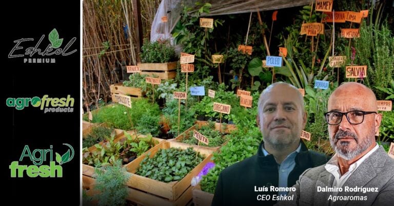 Two men stand in front of a lush herb garden with labeled plant signs; company logos line the left side. - Las2orillas.co: Historias, voces y noticias de Colombia