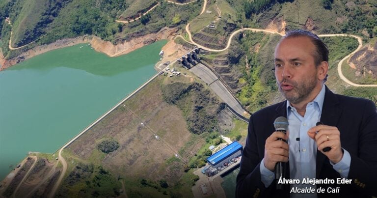 Las2orillas.co: Historias, voces y noticias de Colombia Álvaro Alejandro Eder, Alcalde de Cali, speaking into a microphone with a dam and winding hillside road in the background. - Las2orillas.co: Historias, voces y noticias de Colombia