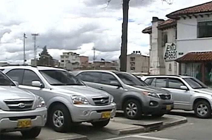 Indignación por el polémico contrato que firmó el Concejo de Bogotá para lavarle los carros a los concejales Row of silver/gray SUVs parked in a lot with a building and cloudy sky in the background. - Indignación por el polémico contrato que firmó el Concejo de Bogotá para lavarle los carros a los concejales