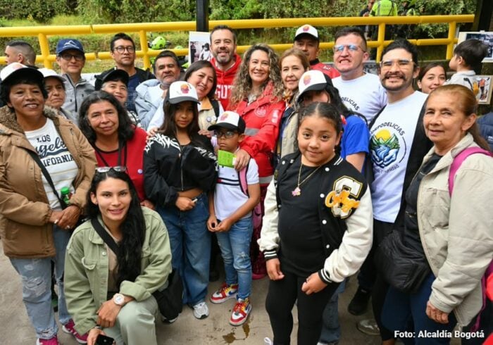 El sendero turístico que lleva a las montañas de Bogotá al que Galán le metió 0 millones para recuperarlo Diverse group posing for a photo at an outdoor event near a yellow railing; many wear caps and jackets. - El sendero turístico que lleva a las montañas de Bogotá al que Galán le metió 0 millones para recuperarlo