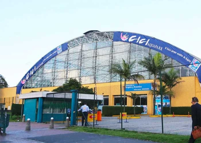 Los mexicanos que manejan Salitre Mágico ponen US millones para remodelar el antiguo Cici Aquapark Entrance to CIC Aquapark with a large curved glass-and-metal arch, yellow building, palm trees, and a few people near the gate. - Los mexicanos que manejan Salitre Mágico ponen US millones para remodelar el antiguo Cici Aquapark