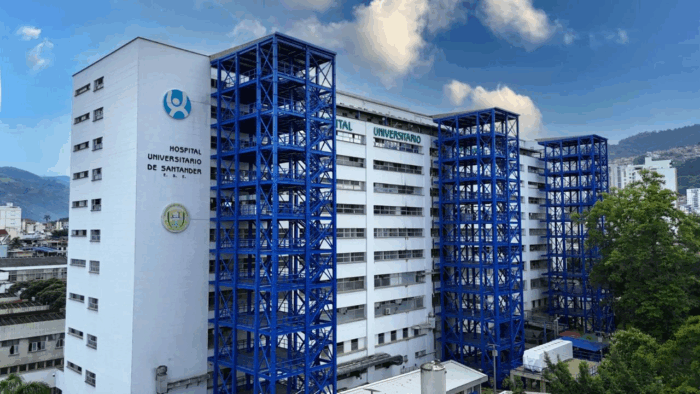 El director del Hospital Universitario de Santander, que deberá enfrentar una multa de 8 millones White hospital building with bold blue steel stair towers and external structures; sign reads 'Hospital Universitario de Santander' amid a blue sky. - El director del Hospital Universitario de Santander, que deberá enfrentar una multa de 8 millones