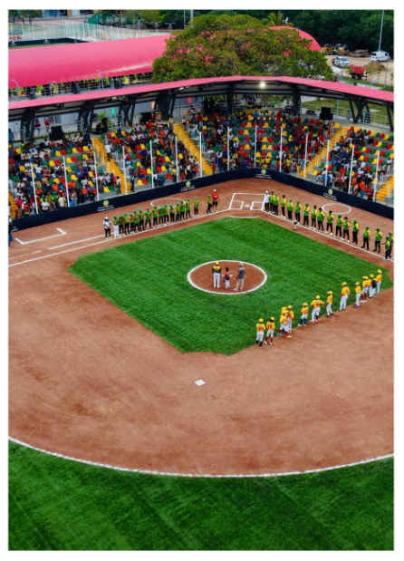 De escombros a nuevo complejo deportivo: así cambia Chambacú en La Heroica Aerial view of a baseball field with players lined up along the baselines while spectators fill colorful seats under a red stadium canopy. - De escombros a nuevo complejo deportivo: así cambia Chambacú en La Heroica