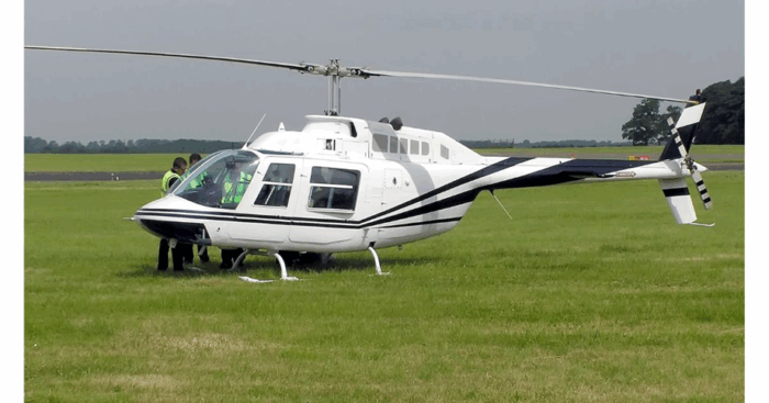 El piloto que lidera una empresa de aviación que se convirtió en la más grande de vuelos en helicópteros y jets privados White helicopter on a grassy airstrip with two people in high-visibility vests near the cockpit. - El piloto que lidera una empresa de aviación que se convirtió en la más grande de vuelos en helicópteros y jets privados