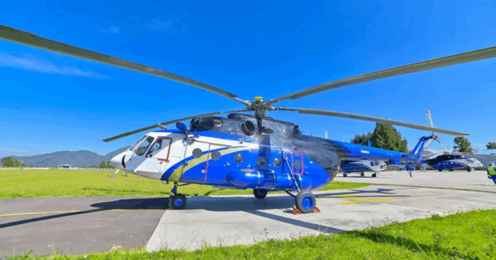 El piloto que lidera una empresa de aviación que se convirtió en la más grande de vuelos en helicópteros y jets privados Blue and white helicopter parked on a concrete tarmac with rotor blades extended under a clear blue sky. - El piloto que lidera una empresa de aviación que se convirtió en la más grande de vuelos en helicópteros y jets privados