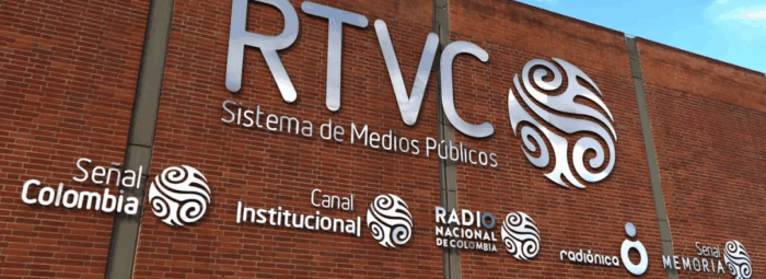 Hollman Morris dejó la olla raspada y la nueva gerente no encontró plata ni para pagar la luz y los sueldos Facade of a brick wall with the RTVC 'Sistema de Medios Públicos' logo and circular decorative emblems; smaller logos read Señal Colombia, Canal Institucional, Radio Nacional de Colombia, radiónica, Señal Memoria. - Hollman Morris dejó la olla raspada y la nueva gerente no encontró plata ni para pagar la luz y los sueldos