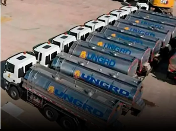El pulso del abogado Gustavo Moreno para evitar que Sneyder Pinilla fuera trasladado a La Picota Row of white-cab tanker trucks parked in a lot, each with a blue cylindrical tank and a yellow logo/mark along the side. - El pulso del abogado Gustavo Moreno para evitar que Sneyder Pinilla fuera trasladado a La Picota