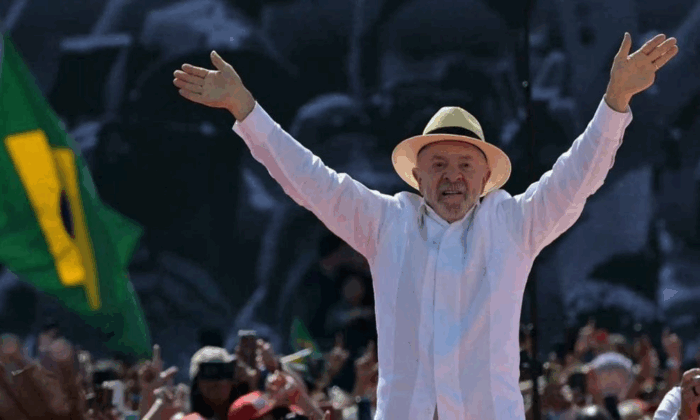 Brasil decide si se queda con Lula o vuelve a la presidencia un Bolsonaro Man in a white shirt and straw hat raises both arms while addressing a cheering crowd at an outdoor rally (no name given). - Brasil decide si se queda con Lula o vuelve a la presidencia un Bolsonaro